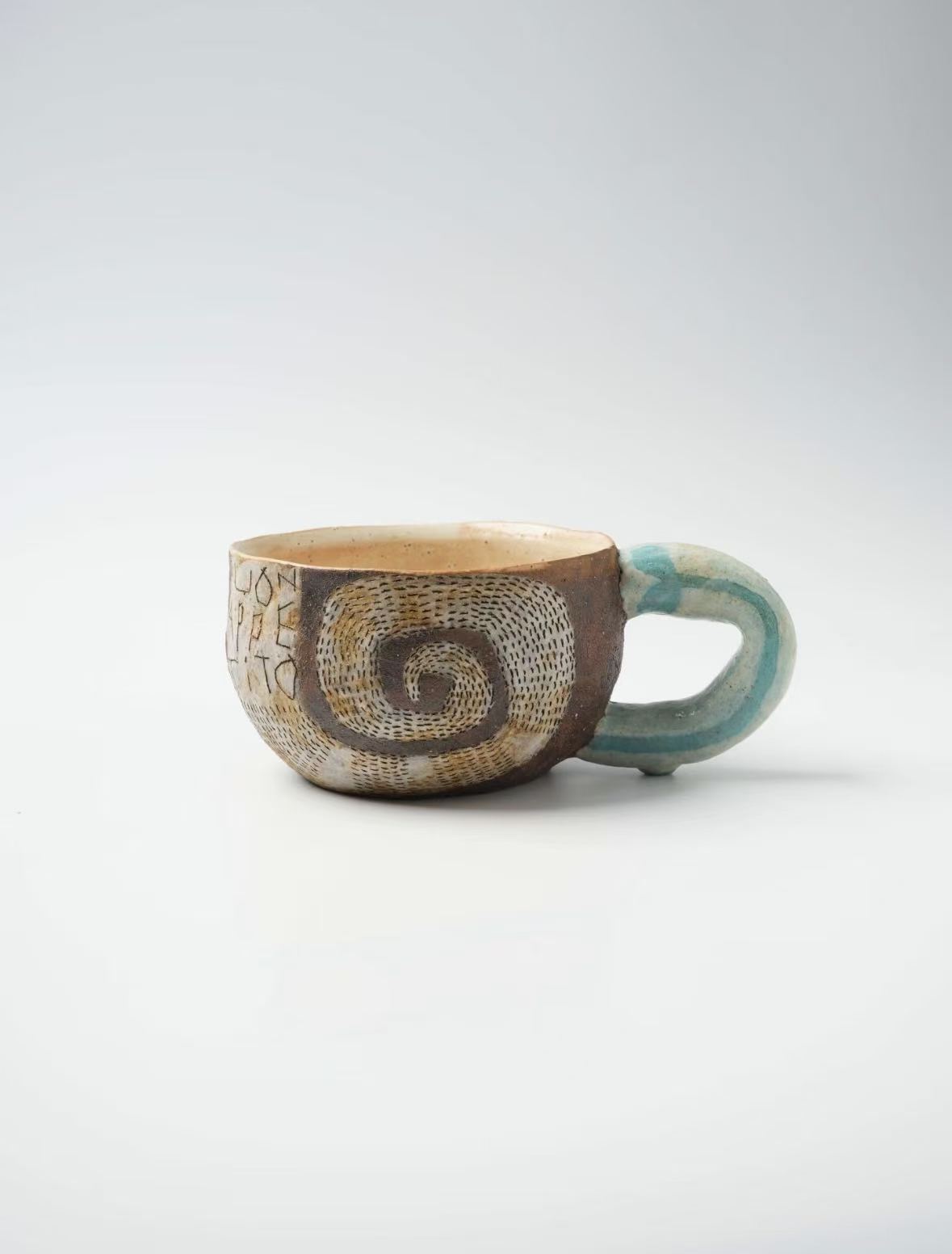 青緑色の持ち手が付いた陶器のカップ